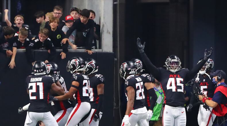 120521 Atlanta: Falcons linebacker Deion Jones (right) and teammates react after defensive lineman Marlon Davidson intercepts Buccaneers quarterback Tom Brady for a pick six at the end of the second quarter in a NFL football game on Sunday, Dec 5, 2021, in Atlanta.   “Curtis Compton / Curtis.Compton@ajc.com”`
