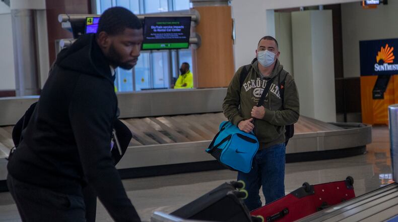 04/28/2020 - Atlanta, Georgia  - A passenger wearing a mask (right) waits as a baggage agent confirms his luggage (left) at the North baggage claim at Atlanta's Hartsfield-Jackson International Airport, Tuesday, April 28, 2020. (ALYSSA POINTER / ALYSSA.POINTER@AJC.COM)