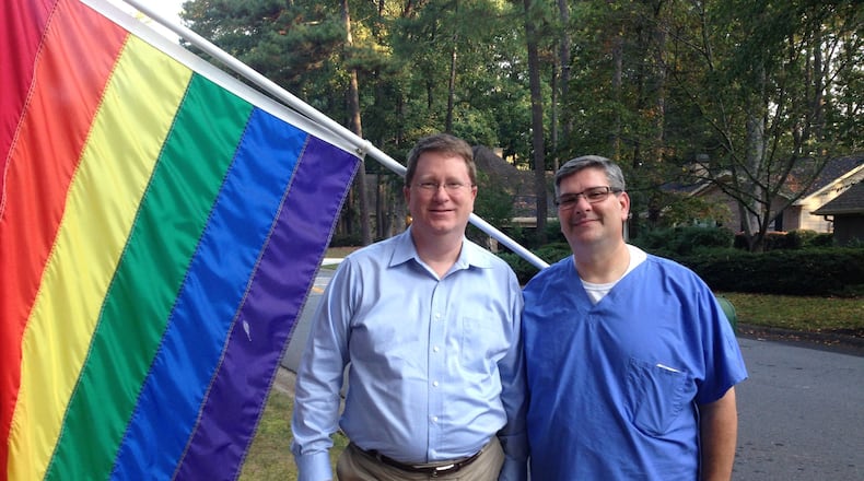Gary Caudill (left) and his partner, Matt Lombardi, stand before the rainbow flag that’s been on display at their Peachtree Corners home since June to celebrate Gay Pride Month. The couple was about to take the flag down when an anonymous resident complained the emblem is offensive. GRACIE BONDS STAPLES / GSTAPLES@AJC.COM