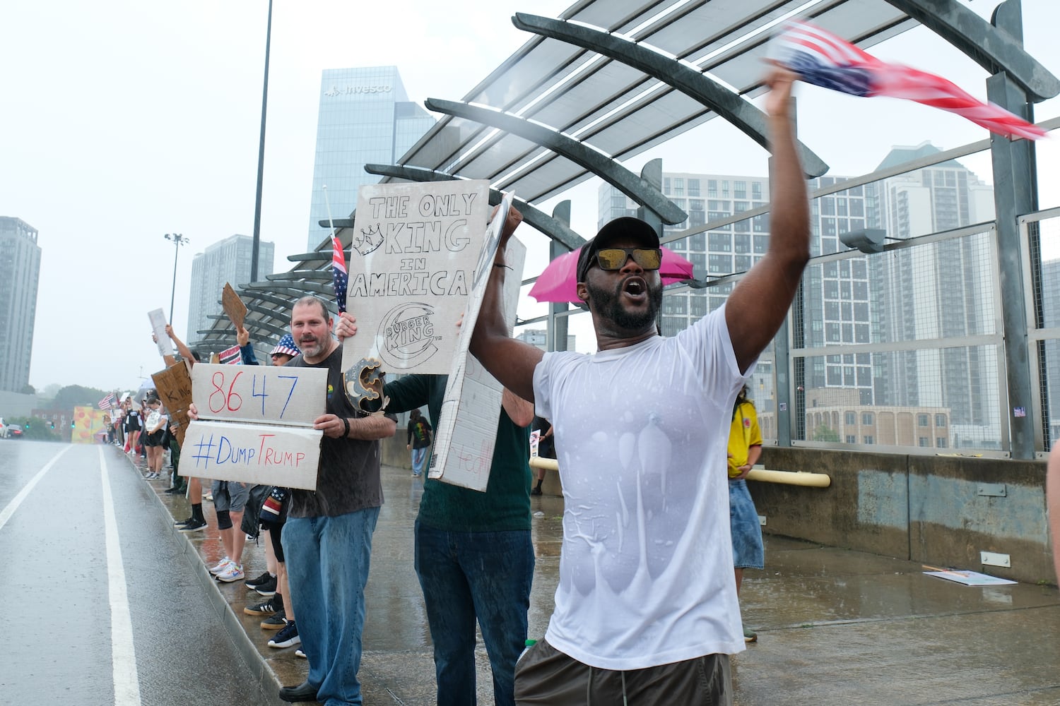 People brave the driving rain on the 17th Street bridge in Atlanta as part of the nation-wide No Kings protests Saturday, June 14, 2025.   Ben Gray for the Atlanta Journal-Constitution