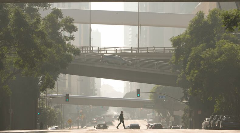 FILE - A person crosses a street as pollution fills the air, Dec. 4, 2024, in Los Angeles. (AP Photo/Andy Bao, File)
