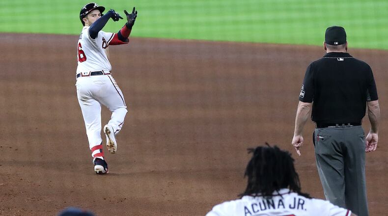 100620 Houston: Atlanta Braves catcher Travis D’Arnaud looks back to the dugout to "stir the drink" in celebration with teammate Ronald Acuna (13) of a three-run homer that gave Atlanta a 7-4 lead over the Miami Marlins during the 7th inning of Game 1 of the National League Division Series Tuesday, Oct. 6, 2020, at Minute Maid Park in Houston. (Curtis Compton / Curtis.Compton@ajc.com)