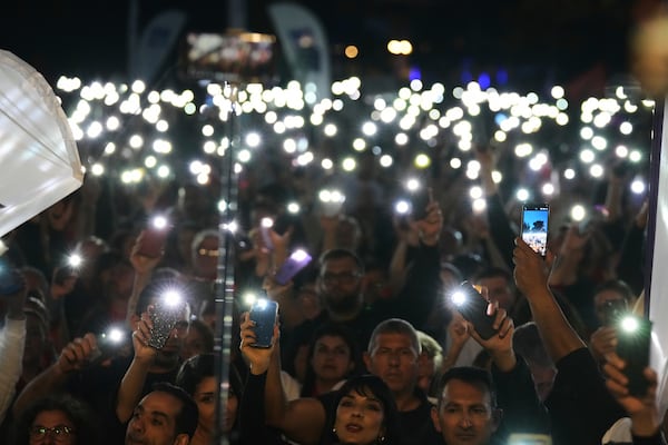 Turkish Cypriot protesters hold the lighted mobile phones aloft as as they gather to protest against what they say is Turkey's attempt to erode their secular roots and to strengthen the hold of political Islam over their society, in the northern half of ethnically divided Cyprus' capital Nicosia, on Friday, May 2, 2025. (AP Photo/Petros Karadjias)