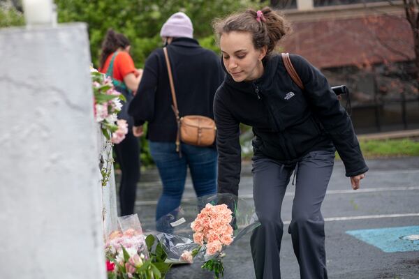 A woman places flowers near a makeshift memorial outside the Gold Spa in Atlanta on Wednesday. (Alyssa Pointer / Alyssa.Pointer@ajc.com)