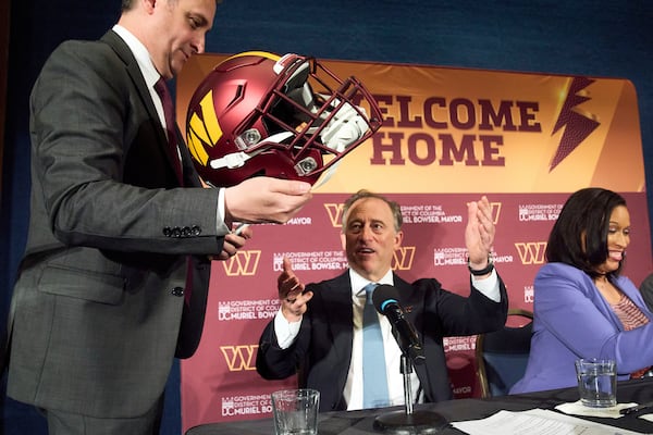 Washington Commanders controlling owner Josh Harris, center, is passed a helmet to sign next to District of Columbia Mayor Muriel Bowser, right, after announcing a new home for the NFL football team on the site of the old RFK Stadium, Monday, April 28, 2025, at the National Press Club in Washington. (AP Photo/Jacquelyn Martin)