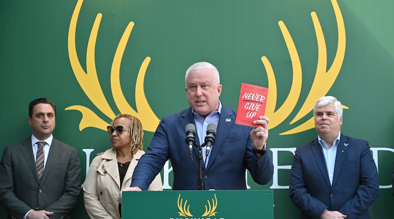 Bill White, chairman and CEO of the Buckhead City Committee, holds a book titled "Never Give Up" as he begins speaking to members of the press during a news conference to discuss an important series of next steps outside the Buckhead City Committee headquarters on Tuesday, February 18, 2022. (Hyosub Shin / Hyosub.Shin@ajc.com)
