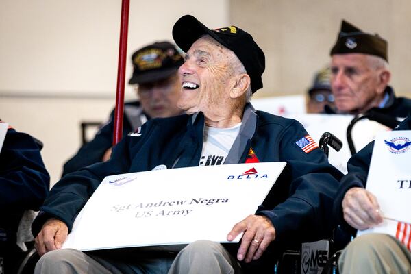 World War II veteran Andrew Negra listens to the Dutchtown High School marching band at the Hartsfield-Jackson international terminal in Atlanta on Wednesday, May 31, 2023. More than 40 World War II veterans boarded a Delta charter flight to Normandy for the 79th anniversary of D-Day. (Arvin Temkar / arvin.temkar@ajc.com)