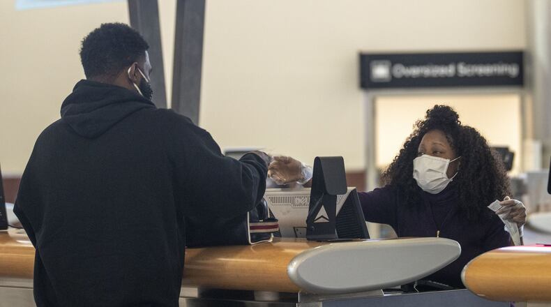 Wearing personal protective equipment, Delta Air Lines customer service agent Kim Franklin (right) communicates with a customer at a Delta Air Lines service desk inside Atlanta’s Hartsfield-Jackson International Airport. (ALYSSA POINTER / ALYSSA.POINTER@AJC.COM)