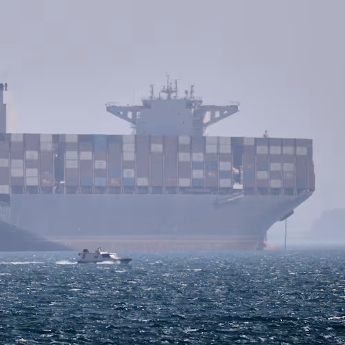 A container ship sits at anchor as a small motorboat passes in the foreground in the Strait of Hormuz off Bandar Abbas, Iran, Saturday, May 2, 2026. (Amirhosein Khorgooi/ISNA via AP)