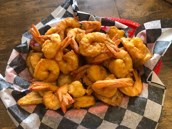 A basket of fried shrimp lined with a piece of black-and-white checkerboard-patterned paper.