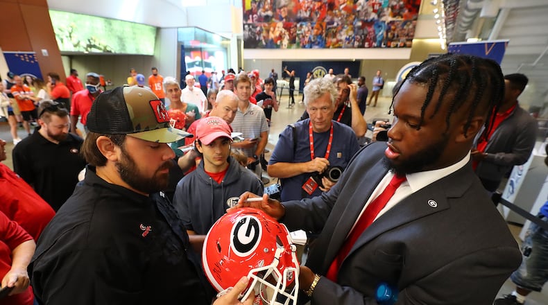 072022 Atlanta: Georgia center Sedrick Van Pran autographs a helmet for a Georgia fan as he arrives at SEC Media Days in the College Football Hall of Fame on Wednesday, July 20, 2022, in Atlanta. “Curtis Compton / Curtis Compton@ajc.com”