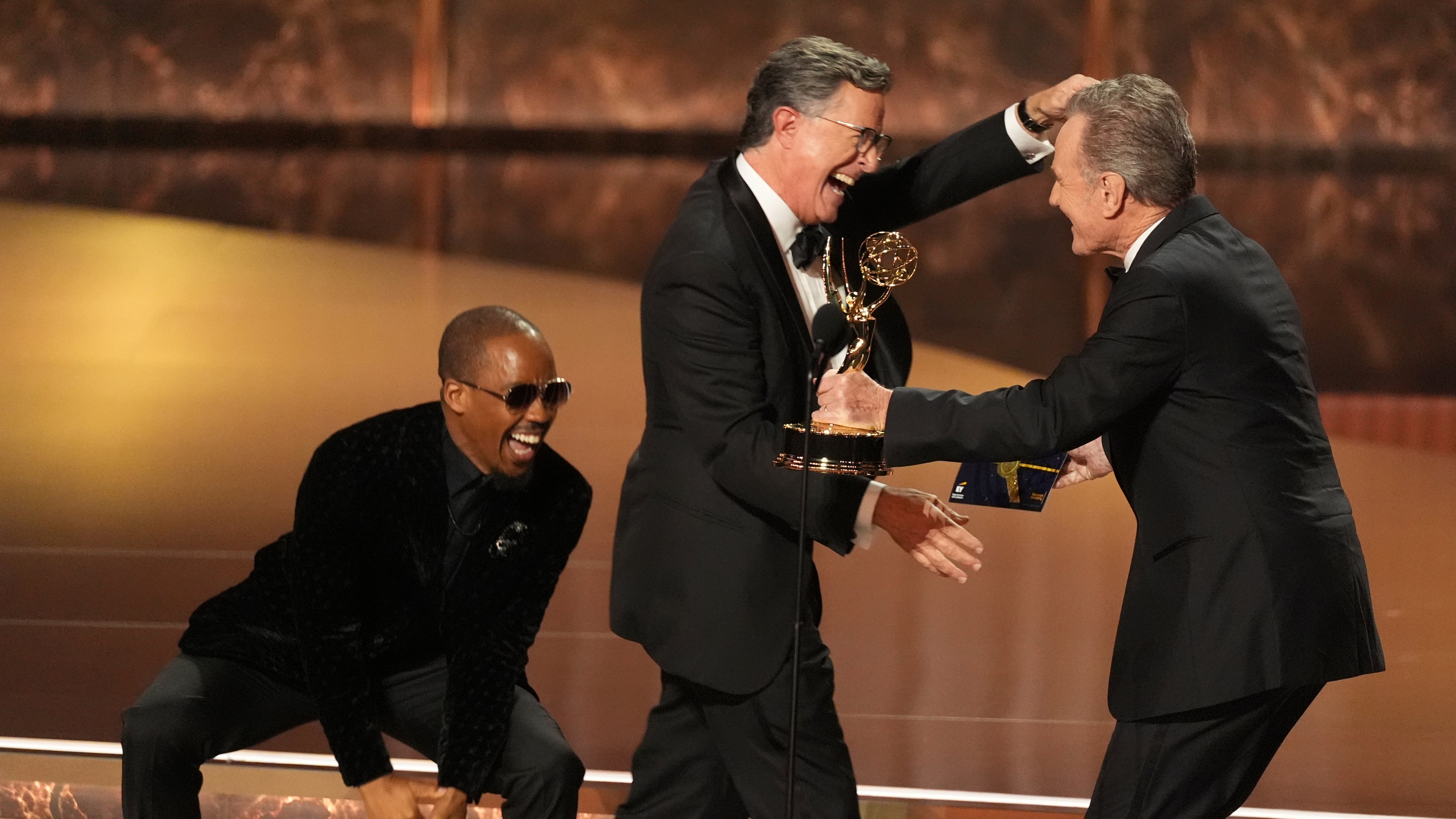 Bryan Cranston, right, presents the award for outstanding talk series to Stephen Colbert, left, for "The Late Show with Stephen Colbert" during the 77th Primetime Emmy Awards on Sunday, Sept. 14, 2025, at the Peacock Theater in Los Angeles. (AP Photo/Chris Pizzello)