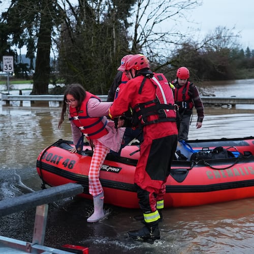 Maery Schine, 11, is helped out of a rescue boat by rescue workers with Chehalis Fire after evacuating with her father Patric, second from left, following flooding after heavy rains in the region Tuesday, Dec. 9, 2025, in Chehalis, Wash. (AP Photo/Lindsey Wasson)