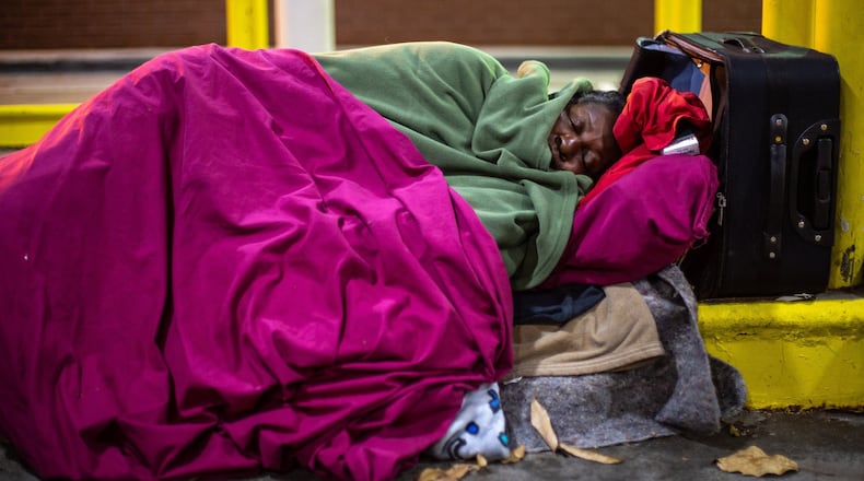 Priscilla Simmons tries to stay warm while sleeping under the drive-thru of a West End bank Wednesday, November 27, 2019. STEVE SCHAEFER / SPECIAL TO THE AJC