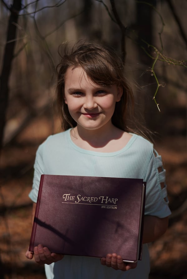 Riley McKibbin, 11, poses for a portrait with her copy of "The Sacred Harp" at Holly Springs Primitive Baptist Church in Bremen, Ga., on Saturday, March 22, 2025. (AP Photo/Jessie Wardarski)