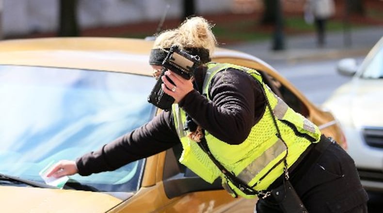 ATL Plus employee takes a photograph of a car that is about to get a parking ticket on Central Ave NW in downtown Atlanta on Friday, Feb. 2020, in Atlanta.ATL Plus is the company contracted to enforce parking in the city of Atlanta.