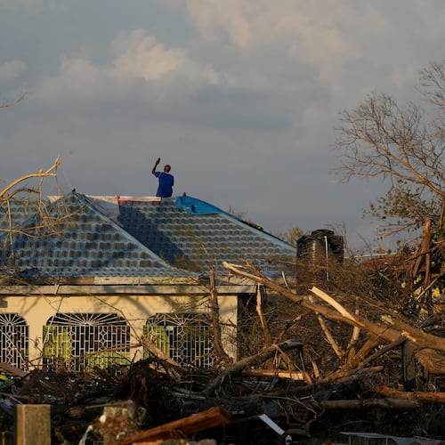 A man searches for cell signal from the roof of his house flooded and damaged by Hurricane Melissa in Black River, Jamaica, Thursday, Oct. 30, 2025. (AP Photo/Matias Delacroix)