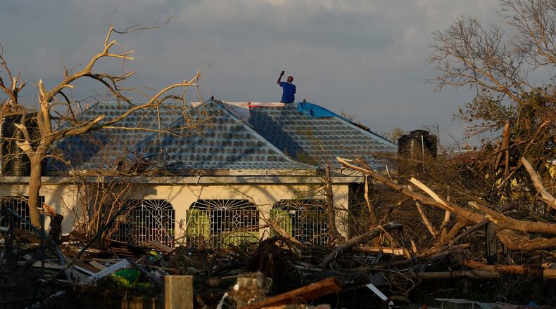 A man searches for cell signal from the roof of his house flooded and damaged by Hurricane Melissa in Black River, Jamaica, Thursday, Oct. 30, 2025. (AP Photo/Matias Delacroix)