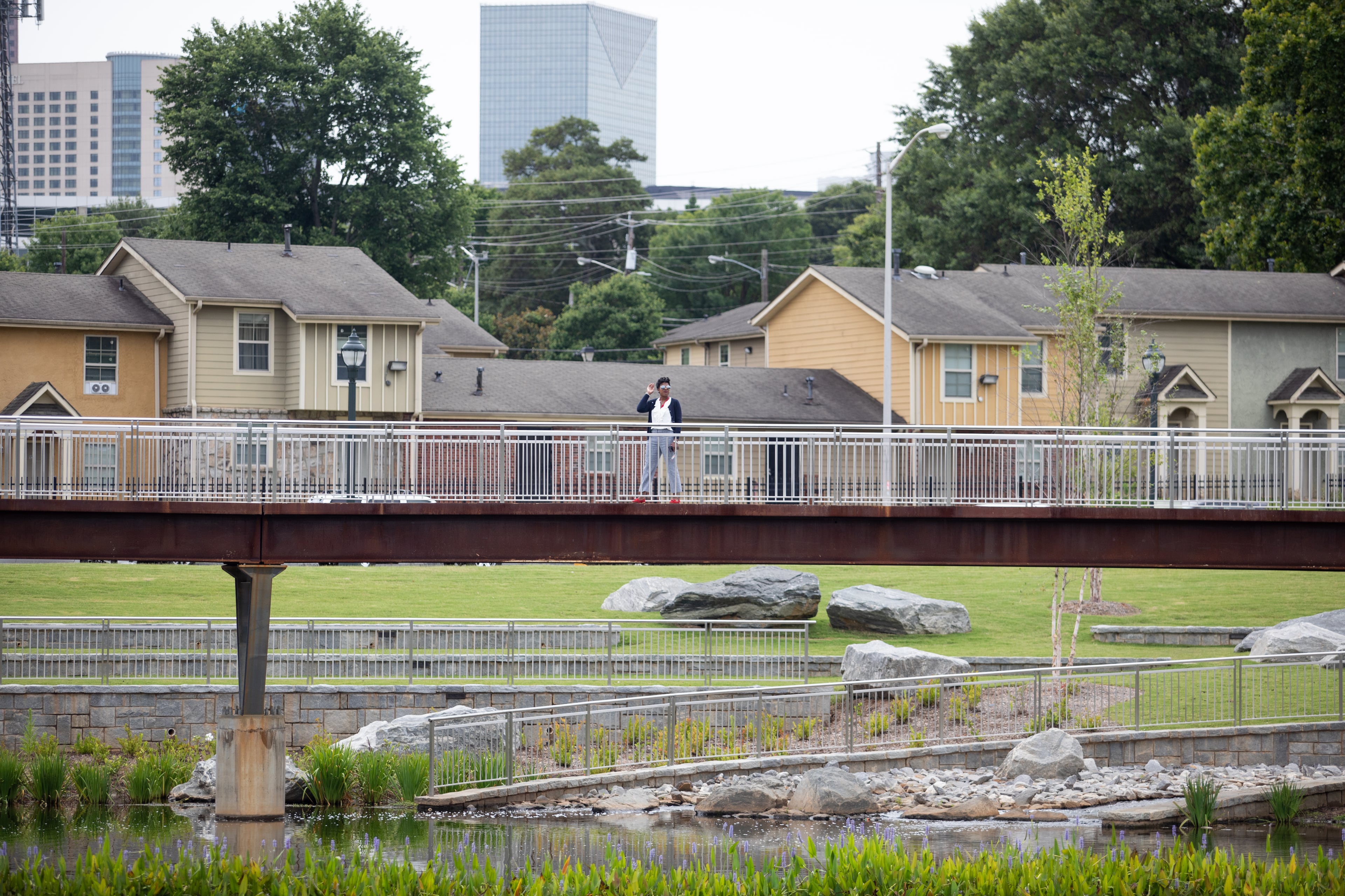 A woman walks across a bridge at Rodney Cook, Sr. Park in Vine City. The park is in a neighborhood that has struggled to manage downtown visitors during sporting events and concerts. (Jenn Finch for the AJC)