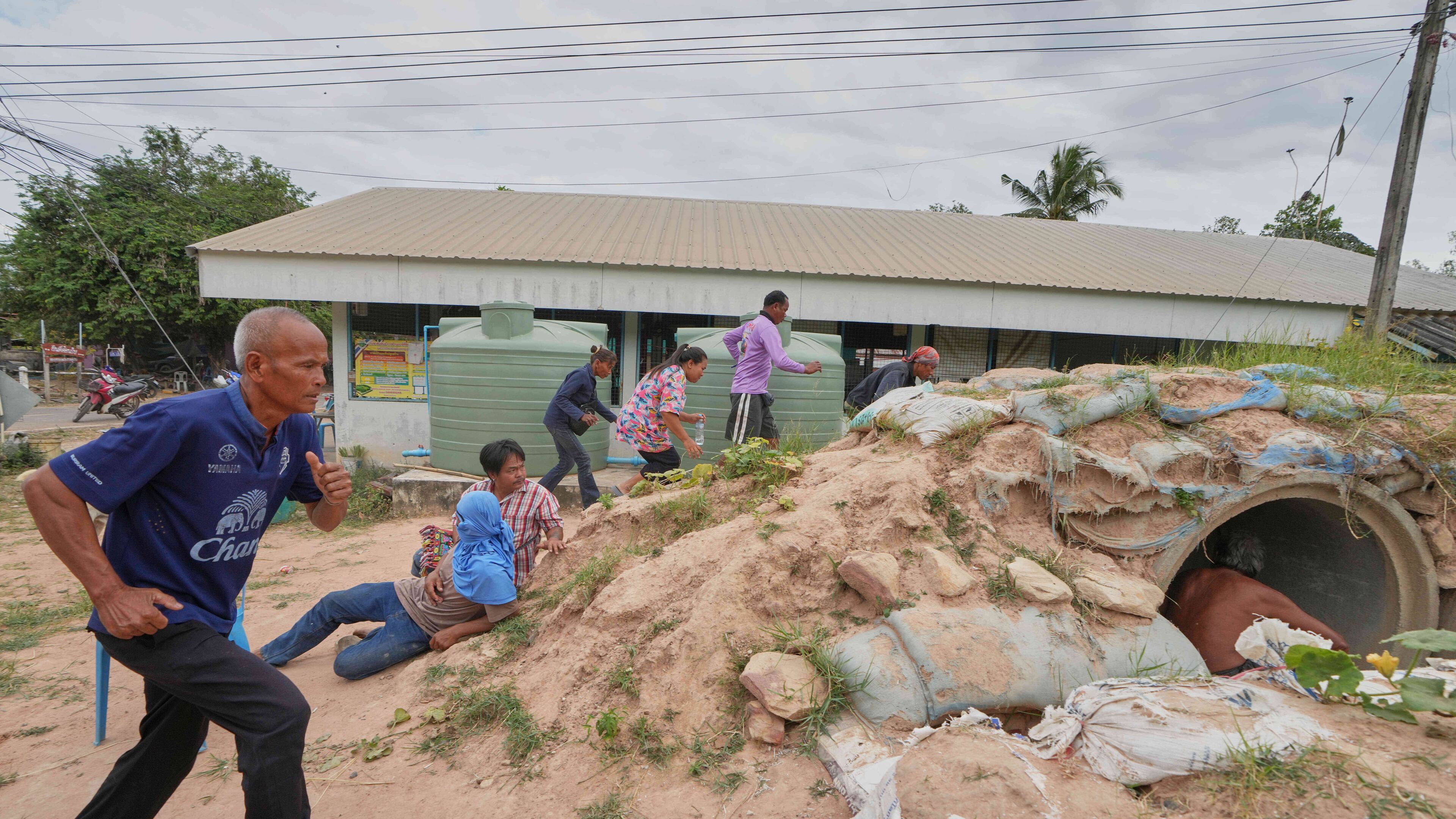 Village security volunteers and resident run into shelter while the blasts sounded too close in Buriram province, Thailand, Friday, Dec. 12, 2025, following renewed border conflict between Thailand and Cambodia. (AP Photo/Sakchai Lalit)