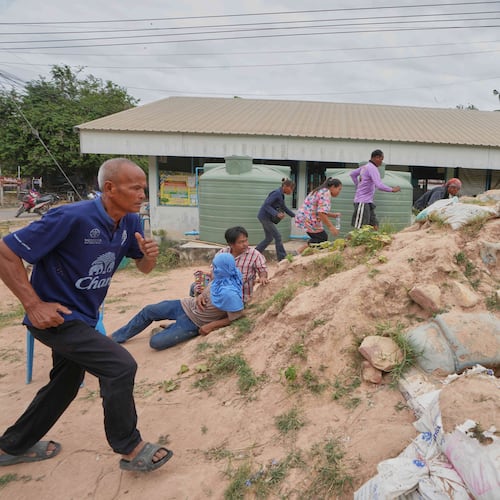 Village security volunteers and resident run into shelter while the blasts sounded too close in Buriram province, Thailand, Friday, Dec. 12, 2025, following renewed border conflict between Thailand and Cambodia. (AP Photo/Sakchai Lalit)