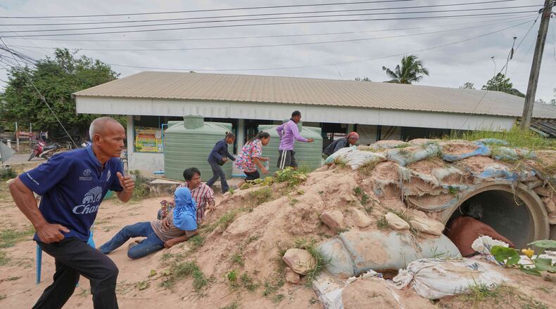 Village security volunteers and resident run into shelter while the blasts sounded too close in Buriram province, Thailand, Friday, Dec. 12, 2025, following renewed border conflict between Thailand and Cambodia. (AP Photo/Sakchai Lalit)