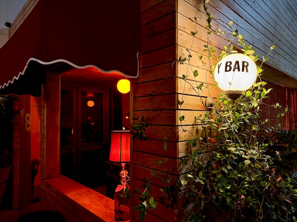 The exterior of a patio bar with a globe lamp lettered with the words Y BAR.