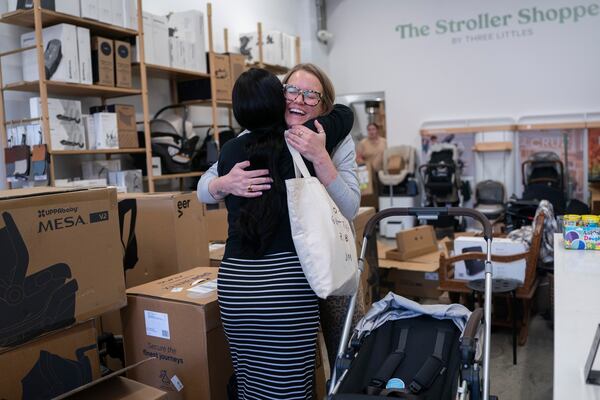 Elizabeth Mahon, right, owner of the baby store Three Littles, and Monique Wallace embrace in reaction to Wallace's new stroller at the Market location in Washington, on Wednesday, April 16, 2025. (AP Photo/Nathan Howard)