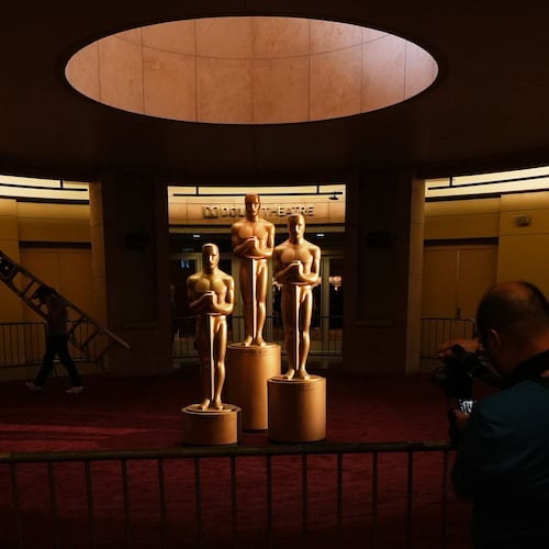 People look on as workers install Oscar statues Saturday, March 14, 2026, at the Dolby Theatre in Los Angeles, in preparation for Sunday's 98th Academy Awards ceremony. (AP Photo/Gregory Bull)