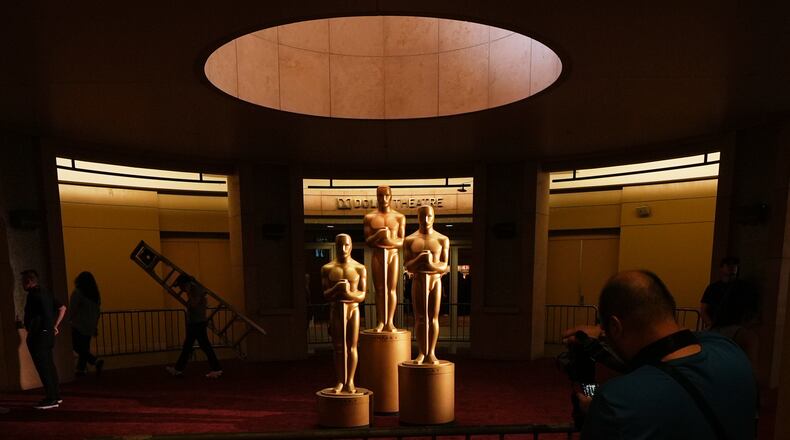People look on as workers install Oscar statues Saturday, March 14, 2026, at the Dolby Theatre in Los Angeles, in preparation for Sunday's 98th Academy Awards ceremony. (AP Photo/Gregory Bull)