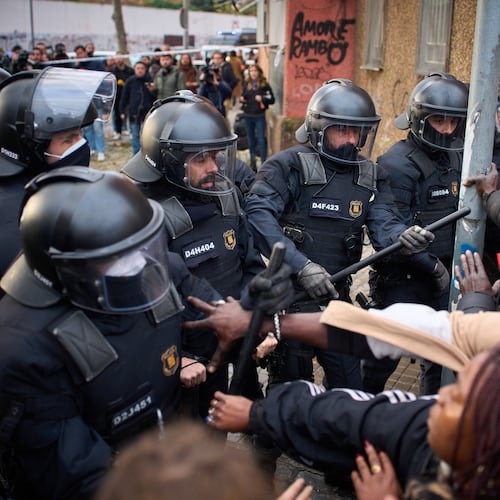 Migrants confront police as they begin carrying out eviction orders at an abandoned school building where hundreds of mostly undocumented migrants had been living, in Badalona, near Barcelona, Spain, Wednesday, Dec. 17, 2025. (AP Photo/Emilio Morenatti)