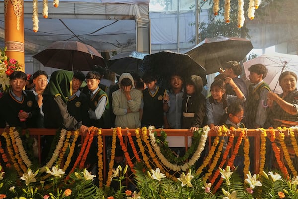 Tibetan school children wait in the rain for the arrival of Tibetan spiritual leader the Dalai Lama to attend an event celebrating his 90th birthday in Dharamshala, India, Sunday, July 6, 2025. (AP Photo/Ashwini Bhatia)