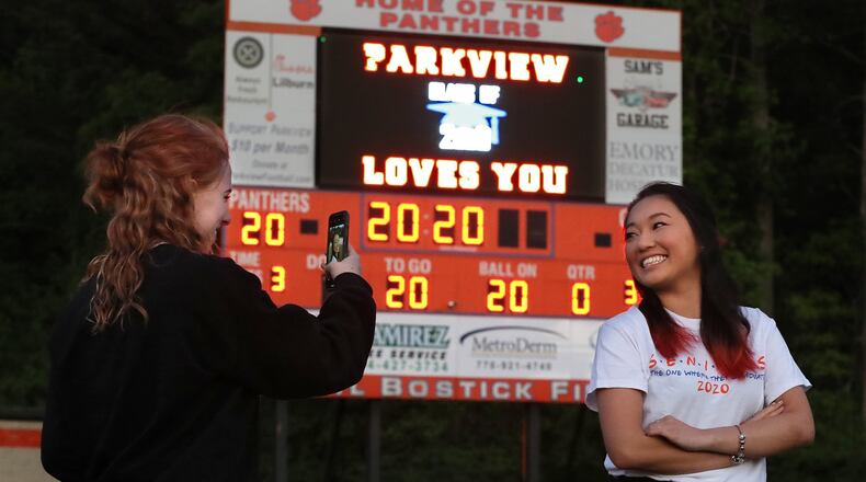 Graduating seniors Jenna Bryant (left) and Kelsey Watkins snap photos of each other in the “Big Orange Jungle,” Hugh Buchanan Field, as it is lit up to honor the class of 2020 at Parkview High School on Tuesday, April 14, 2020, in Lilburn. Every week night at 8:20 pm (20:20 military time) athletic director Nick Gast turns on the scoreboard and stadium lights for 20 minutes and 20 seconds. CURTIS COMPTON / CCOMPTON@AJC.COM