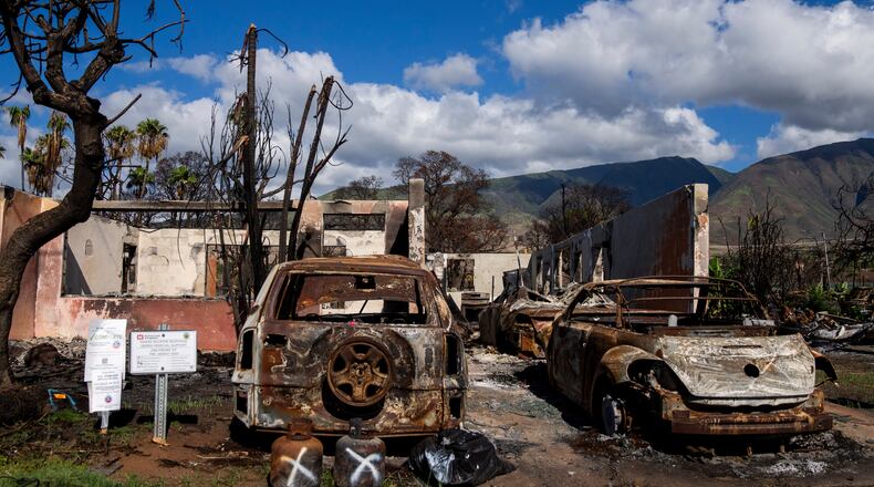 FILE - Burned cars and propane tanks with markings on them sit outside a house destroyed by wildfire, Friday, Dec. 8, 2023, in Lahaina, Hawaii. (AP Photo/Lindsey Wasson, File)