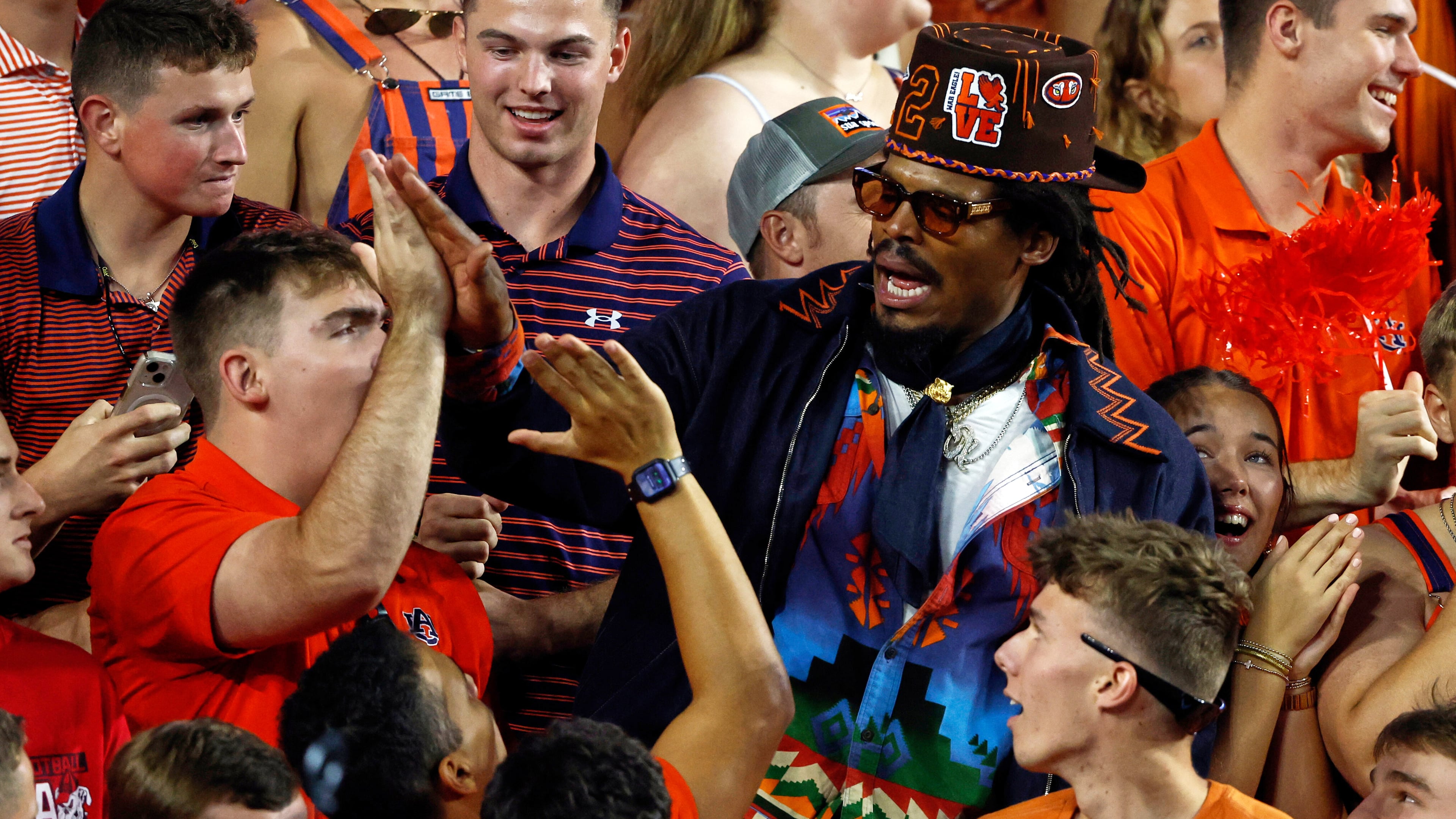 Former Auburn quarterback and NFL player Cam Newton celebrates with fans after a play during the first half of an NCAA college football game against Georgia, Saturday, Oct. 11, 2025, in Auburn, Ala. (AP Photo/Butch Dill)