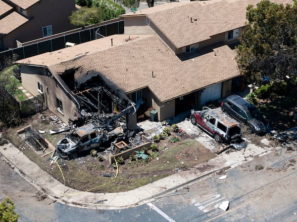 Debris covers the ground after a small plane crashed into a San Diego neighborhood, setting homes and cars on fire and forcing evacuations early Thursday, May 22, 2025. (AP Photo/William Liang)