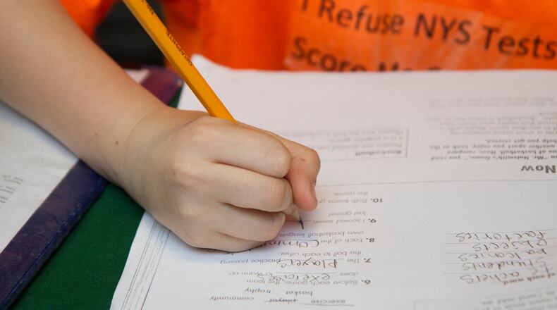 FILE -- Blake Carnright, 10, does homework -- the message on his shirt reflects his mother's decision to opt out of standardized state tests -- at home in Ilion, N.Y., April 22, 2015. This year, twenty percent of New York State?s third through eighth graders sat out at least one standardized test based on new Common Core academic standards, according to education officials, a sign of increasing resistance to testing. (Emma Tannenbaum/The New York Times)