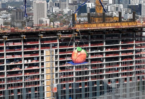 A gigantic peach is lifted up to the top during topping out ceremony of Signia by Hilton Atlanta at Georgia World Congress Center, Thursday, March 23, 2023, in Atlanta. Plans are in motion for GWCCA’s new headquarter hotel Signia by Hilton Atlanta. Featuring close to 1,000 rooms, this premier full-service hotel will sit on the northwest corner of the campus, adjacent to Building C of Georgia World Congress Center. (Hyosub Shin / Hyosub.Shin@ajc.com)