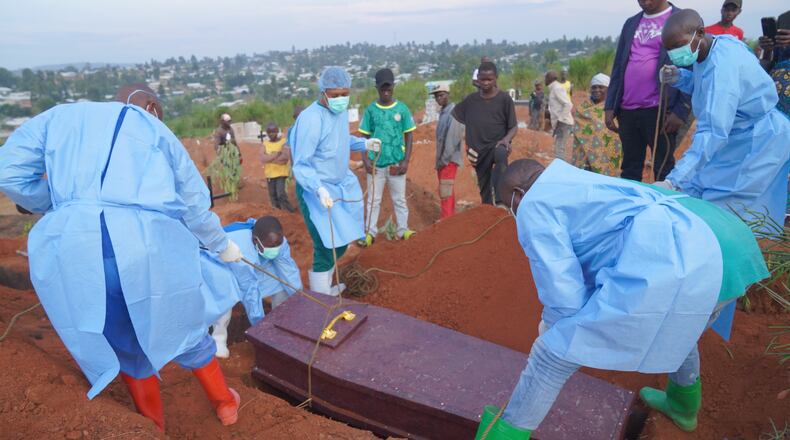 People dressed in protective gear lower into a grave the coffin containing the remains of 6-year-old Baudjo Baraka Jules, who died of Ebola, in Bunia, Ituri province, eastern Congo, Tuesday, Aug. 18, 2026. (AP Photo/Dieudonne Dirole)