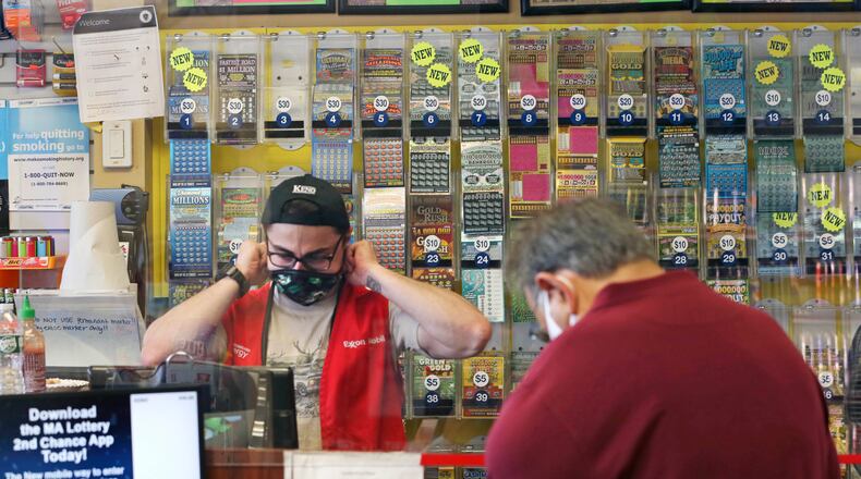A clerk adjusts his protective mask while waiting on a masked customer at Ted's Stateline Mobil on Wednesday, June 24, 2020 in Methuen, Mass.