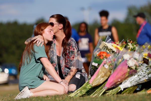 Stacey Andrews and her daughter Payton Owen, pay their respects by a memorial outside the school in 2024, after a shooting that killed two teens and two teachers. (Miguel Martinez/AJC)
