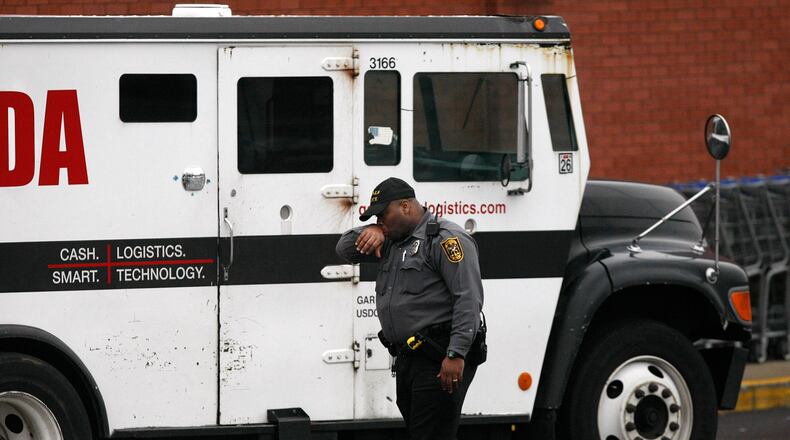 A DeKalb County police officer looks over the scene where 2 men killed a guard in a daring armored car robbery at the Kroger on Lavista Road at North Druid Hills in Atlanta on Tuesday, March 15, 2011.