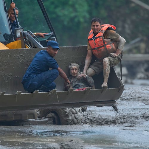 Rescuers use an earthmover to carry a victim of flash flooding to safety along the Trishuli River in Nepal's Nuwakot district, Wednesday, Aug. 26, 2026. (AP Photo/Niranjan Shrestha)