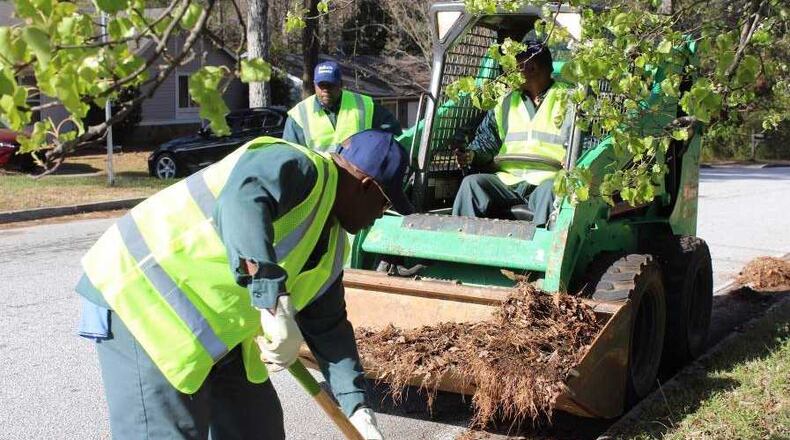 In areas too thick for a street sweeper to clean, crews manually dig debris to clear the curb. Photo via DeKalb County