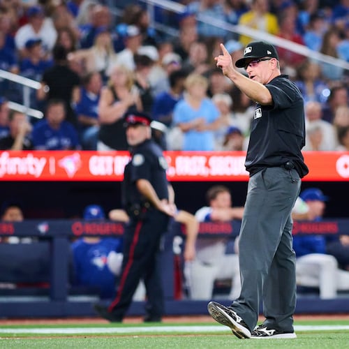 Umpire Chris Guccione, center, announces a rules check during an umpire review during the seventh inning of a baseball game between the Toronto Blue Jays and the Boston Red Sox in Toronto, Monday, Aug. 10, 2026. (Sammy Kogan/The Canadian Press via AP)