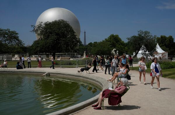 People walk past the Olympic cauldron at the Tuileries Gardens, ahead of its nightly summer relaunch starting June 21, in Paris, Thursday, June 12, 2025. (AP Photo/Michel Euler)