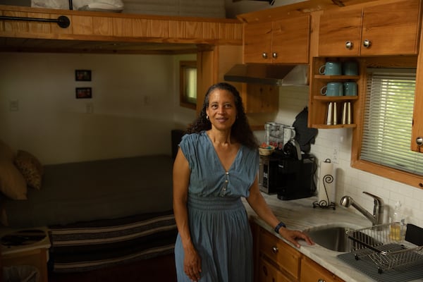 Cabbagetown resident Nadia Giordani poses for a portrait in her 300-square-foot tiny home in her backyard that she uses as a short-term rental to help her pay for rising property taxes in the area. (Riley Bunch/AJC)