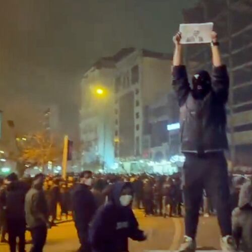 In this frame grab from video obtained by the AP outside Iran, a masked demonstrator holds a picture of Iran's Crown Prince Reza Pahlavi during a protest in Tehran, Iran, Friday, January. 9, 2026. (UGC via AP)