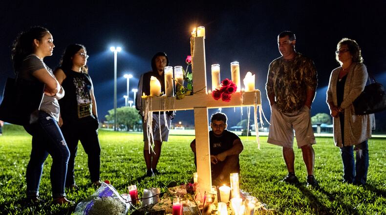 Mourners visit one of 17 crosses after a candlelight vigil for the victims of the shooting at Marjory Stoneman Douglas High School in Parkland on Thursday. (Greg Lovett / The Palm Beach Post)