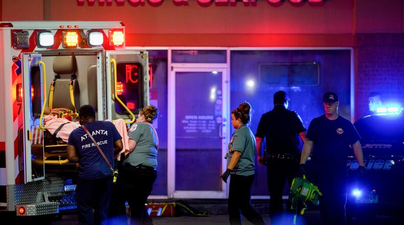 Atlanta fire and Grady EMS crews load a shooting victim into an ambulance on Metropolitan Parkway. He was found at a Chevron gas station early Tuesday after being shot at a food mart a block south.